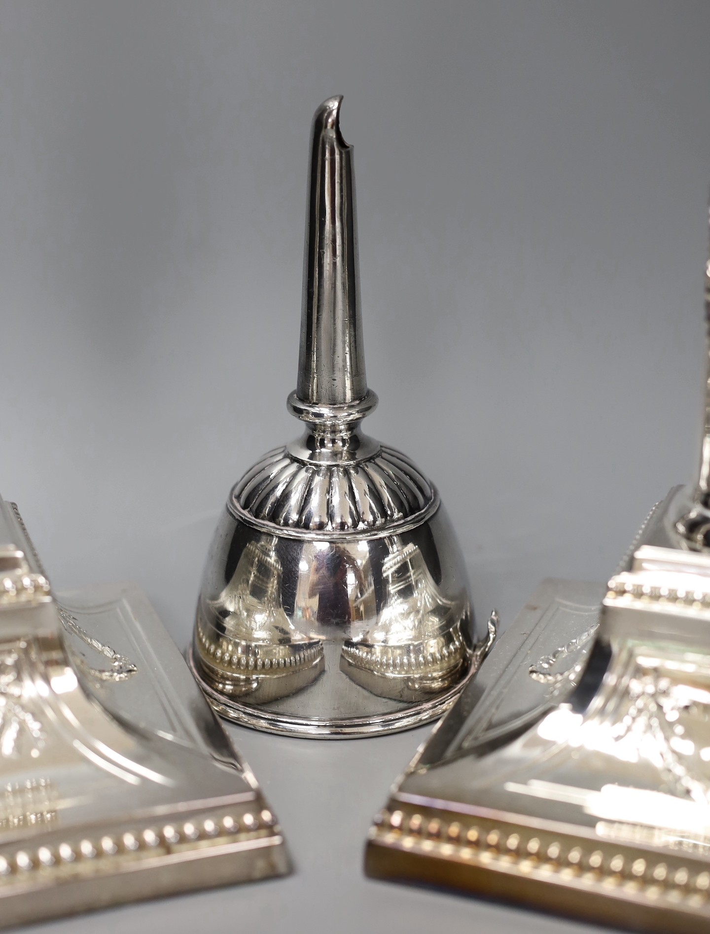 A pair of silver plated candlesticks, a plated wine funnel and a plated candle extinguisher, Plated candlesticks 34 cms high.